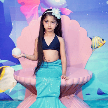 Child dressed as a mermaid sitting on a shell-shaped seat in an underwater-themed area at Wooray Hyderabad.