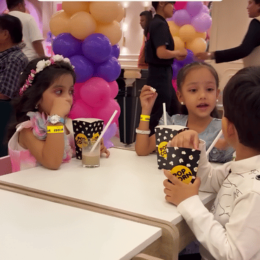 Children enjoying popcorn and party treats during a celebration at Wooray Hyderabad.